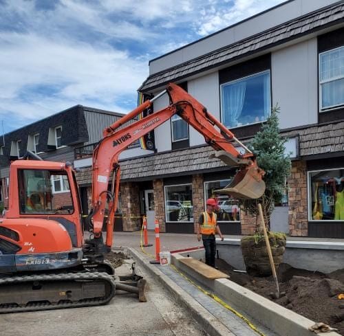 excavator operator reviewing site safety plan before beginning trench excavation at a Kamloops BC landscaping project